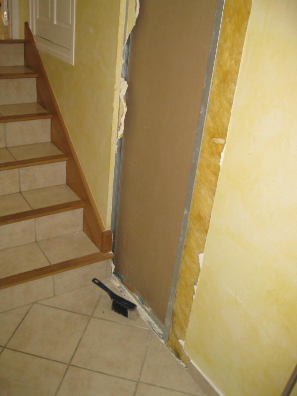 The existing opening is in the middle of the hall, which wouldn't work out. So he chipped away at a wall that was adjacent to stairs that led down into the garage.