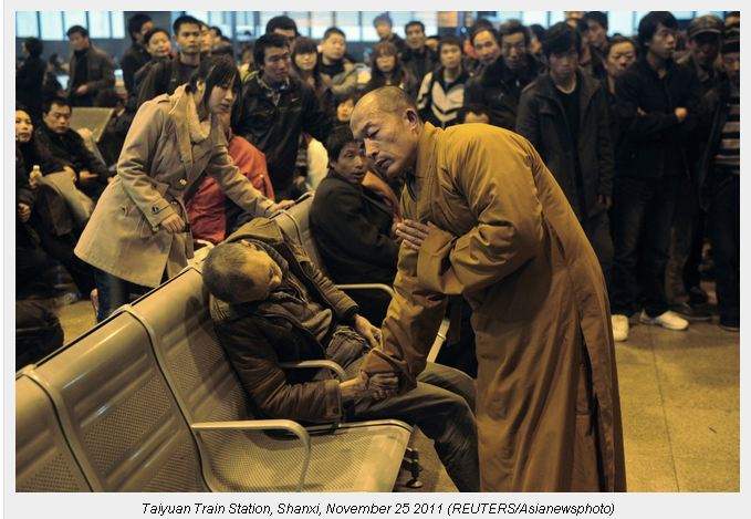 Amonk prays for a dead man in the station hall of the Shanxi Taiyuan Train Station, China. The man died suddenly of natural causes while waiting for a train.