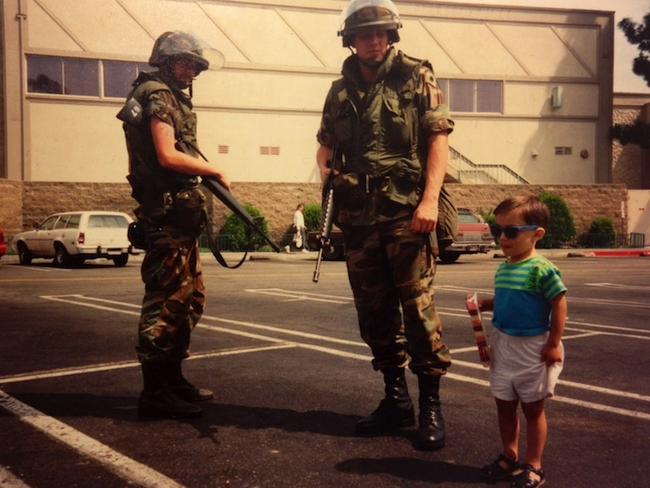 During the 1992 riots in Los Angles, a young child poses with National Guard troops.