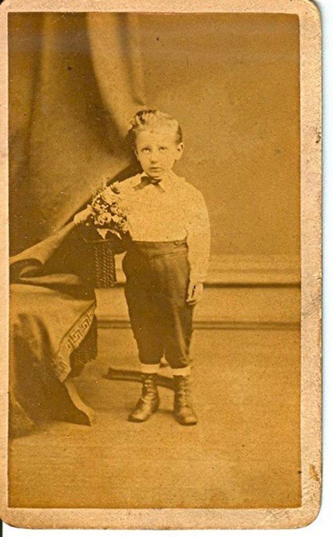 Notice the odd position of the curtain behind the boy? It's likely there was someone behind it holding the boy's head up.