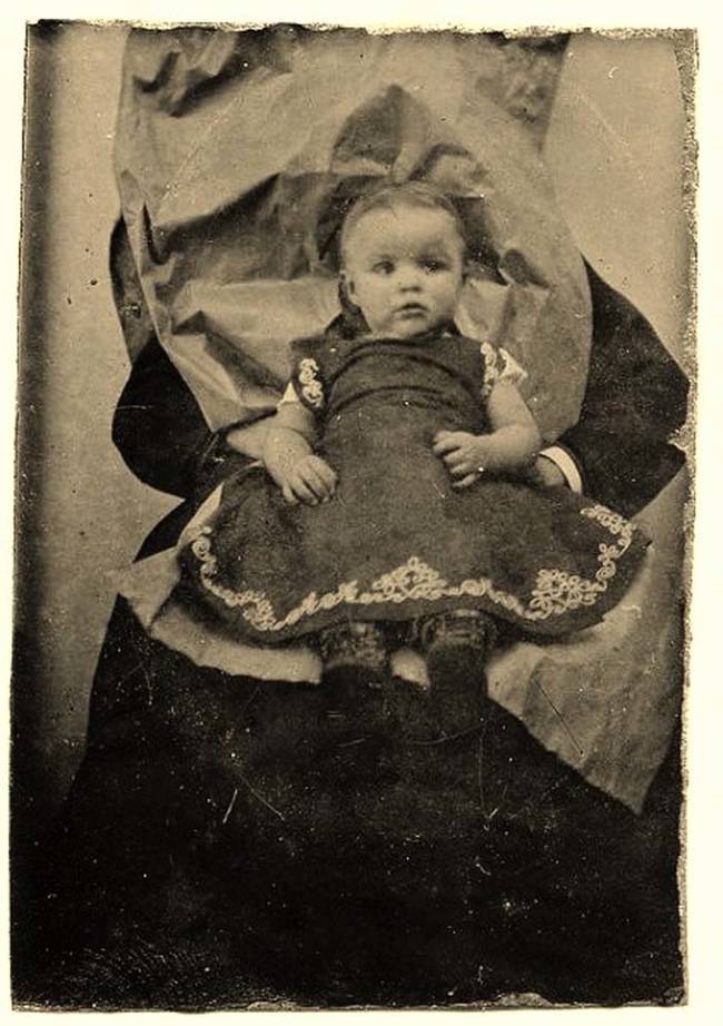 See anything strange about the background? This girl is sitting on someone's lap. The person held her in place while the photo was taken.