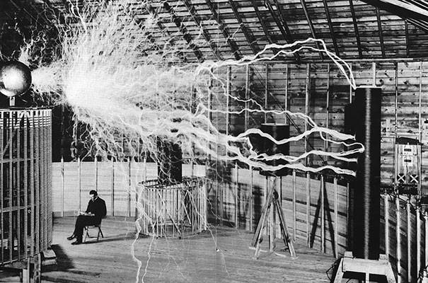 Nikola Tesla sitting in the laboratory with his magnifying transmitter.