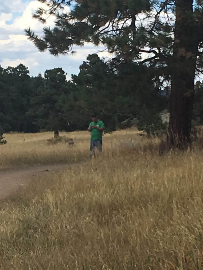 He didn't like having his picture taken, so his girlfriend sneakily took one while standing at a distance.As you can see, she captured a strange figure crouching behind him that she hadn't seen with her own eyes.
