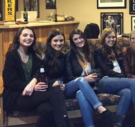 Even with a closer look it's hard to tell what's going on, but if you study the crossed leg of the woman farthest to the left, you might make out what looks like another leg with the same color of jeans blended in.