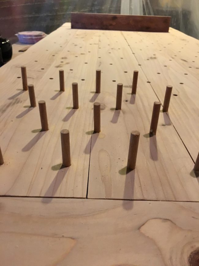 Next, he mapped out and drilled holes for the dowel rods that would guide the balls down to the mugs, then hammered them in with a rubber mallet.
