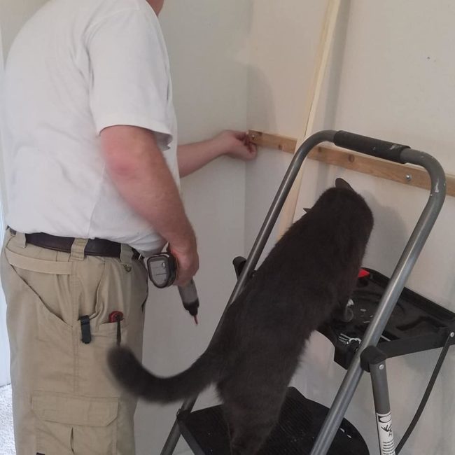 With the main frame installed, they began attaching individual pegboards, using studs and anchor screws to secure them to the wall.