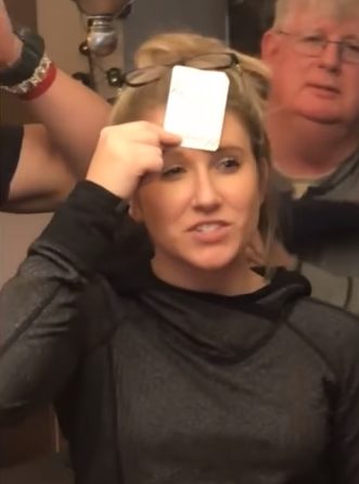 The particular game they were playing involves holding up a card on your forehead. Little did this lady know that her boyfriend had picked out a special one just for her.